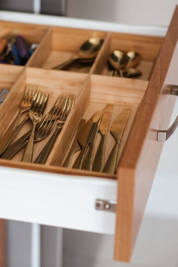 A small apartment kitchen with tiered corner shelves inside cabinets filled with kitchen items, showing an organized and space-efficient layout.